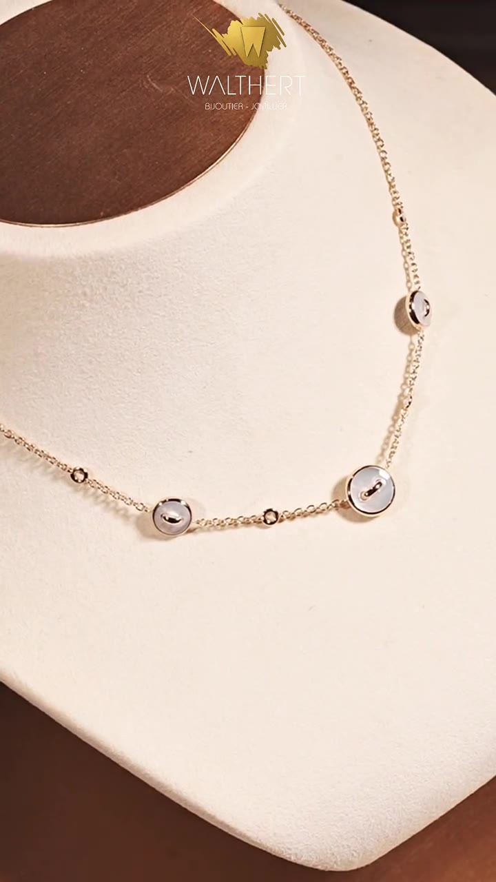 Collier fin en or à motifs ronds sertis, présenté sur un buste en boutique
